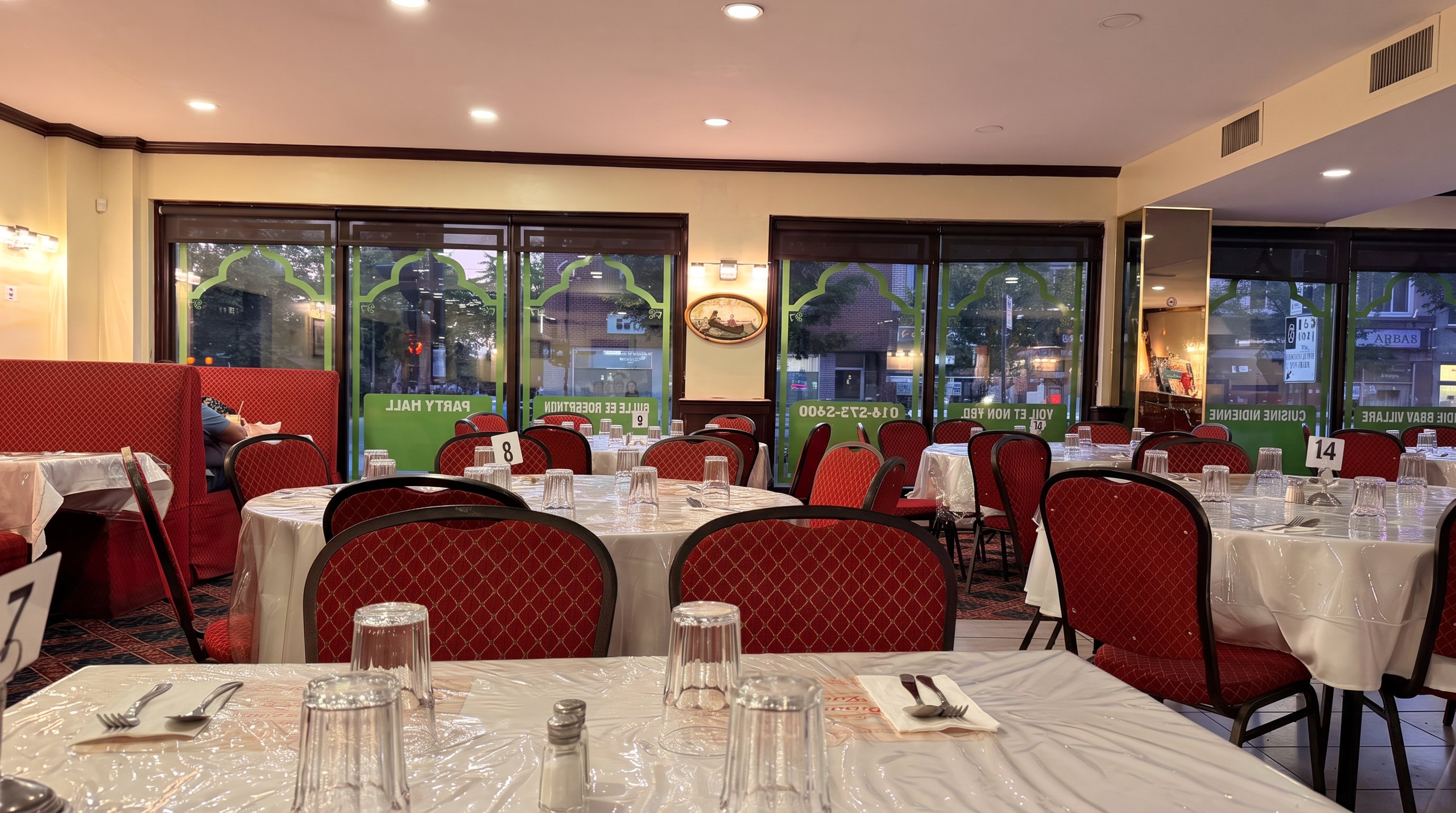India Beau Village dining room — white tablecloths, red chairs and green arch windows on Rue Jarry; enhanced rendition of our photo