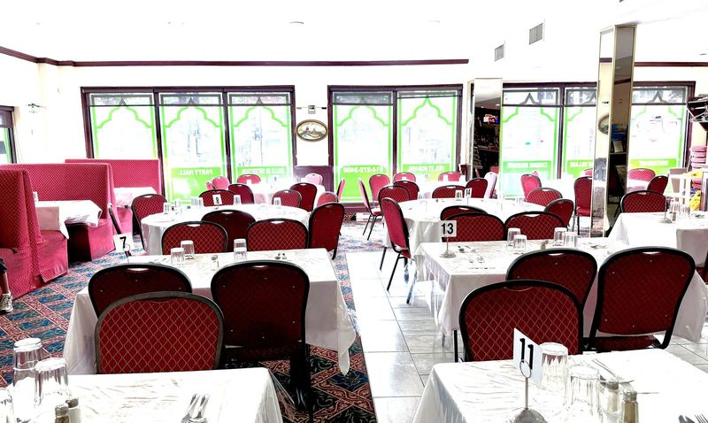 The dining room in daylight — red chairs, green arches and set tables (photo from August 2026)