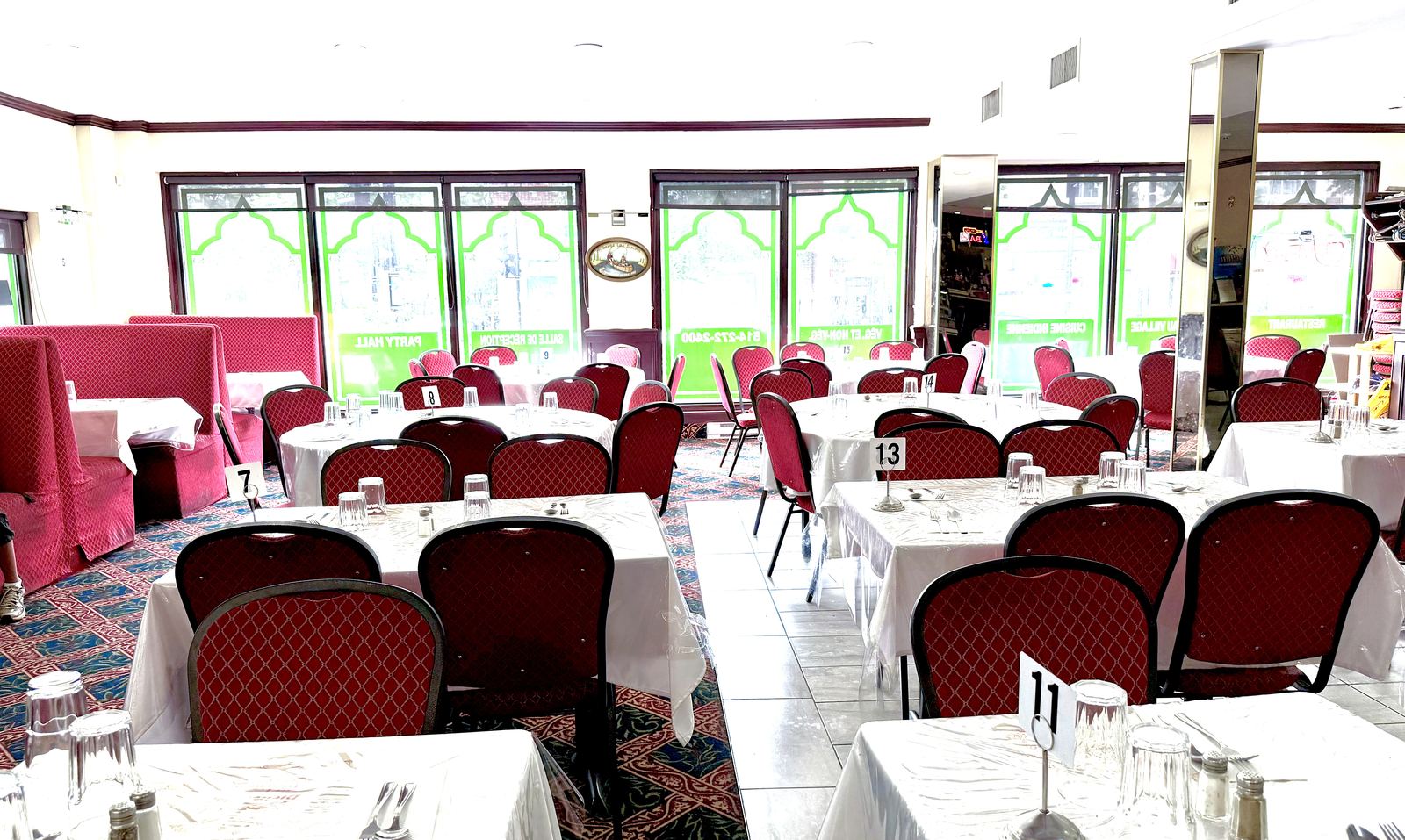 La salle à manger en plein jour — chaises rouges, arches vertes et tables dressées, photographiée cette semaine